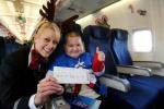 Smiling Fantasy Flight passenger giving a thumbs up with a United flight attendant wearing reindeer antlers