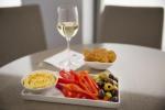 Image of hummus, pita thins, olives, red bell pepper slices and a glass of white wine