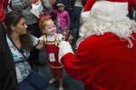 Little girl smiling as Santa hands her a present