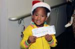 Little girl in Santa hat showing off her boarding pass to see Santa at the North Pole