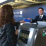 Image of male United service desk employee handing female customer her United ticket