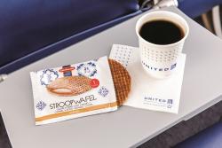 Cup of coffee and stroopwaffle on airplane tray table
