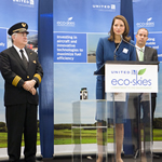 Image of woman giving speech in front of Eco-Skies banners
