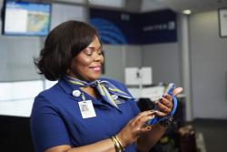 Female flight attendant looking at iPhone in her hand at gate
